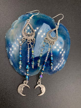 Load image into Gallery viewer, These three-strand chandelier style earrings offer an ornate and eye-catching look with their whimsical blue celestial charm accents adorned with smiling crescent moon designs. Perfect for creating a fairy princess, witchy, or boho aesthetic, they provide plenty of movement and can easily be added to any jewelry collection. Measurements: 3 1/2” in length