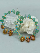 Load image into Gallery viewer, These Aventurine Stone Chip Beaded Hoop Earrings feature natural aventurine stone chips, turquoise, and gold glass beads. The amber-tone pressed glass leaf charm has an iridescent shimmer finish, with subtle accents of gold, purple, blue, and pink. Measurements: 2" length