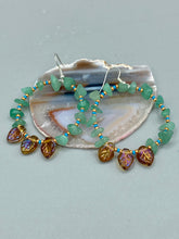 Load image into Gallery viewer, These Aventurine Stone Chip Beaded Hoop Earrings feature natural aventurine stone chips, turquoise, and gold glass beads. The amber-tone pressed glass leaf charm has an iridescent shimmer finish, with subtle accents of gold, purple, blue, and pink. Measurements: 2" length