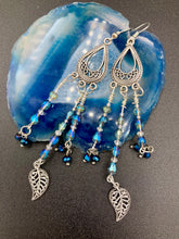 Load image into Gallery viewer, Blue Moroccan Inspired Large Chandelier Earrings. Three strands of beautiful blue and iridescent glass beads with intricate silver plated leaf charms create a lot of movement. Versatile, perfect for whimsical fairy princes, good witch, hippie nature lovers looks. These earring will compliment any look. Measurements: 3 1/2” in length
