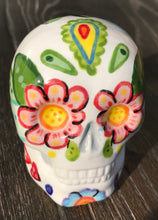 Load image into Gallery viewer, Inspired by nature, this ceramic skull statuette is full of vibrant color and intricate details that I hand painted. The primary color is white with multi-color floral motifs that are painted across the skull, along with hearts and leaves and lively colorful accents around the entire skull.