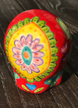 Load image into Gallery viewer, This ceramic skull statuette is a stunning piece of art inspired by nature. Its vibrant red hue is decorated with multi-color floral motifs, hearts, leaves and colorful accents, creating a beautiful piece of hand-painted, Day of the Dead-themed art. Measurements: H 2 3/4” x W 2” x D 2”