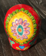 Load image into Gallery viewer, This ceramic skull statuette is a stunning piece of art inspired by nature. Its vibrant red hue is decorated with multi-color floral motifs, hearts, leaves and colorful accents, creating a beautiful piece of hand-painted, Day of the Dead-themed art. Measurements: H 2 3/4” x W 2” x D 2”