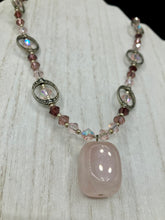 Load image into Gallery viewer, This exquisite necklace features a soft pink Rose Quartz pendant with multi-colored glass beads that transition from iridescent pink, to light purple and darker shades of purple. The sequence of beads complements the Rose Quartz pendant's delicate hue, and is accompanied with a set of subtly-styled matching earrings for a complete look. Measurements: Necklace is 16 1/2”
