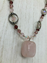 Load image into Gallery viewer, This exquisite necklace features a soft pink Rose Quartz pendant with multi-colored glass beads that transition from iridescent pink, to light purple and darker shades of purple. The sequence of beads complements the Rose Quartz pendant's delicate hue, and is accompanied with a set of subtly-styled matching earrings for a complete look. Measurements: Necklace is 16 1/2”