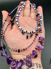 Load image into Gallery viewer, The Genuine Amethyst Natural Gemstone Adjustable Chocker Style Glass Beaded Necklace features vibrant violet and white tones. Its unique draped beading creates a beautiful style with a series of short strands of glass beads for movement and a longer strand with a multitude of amethyst nugget beads. The collar necklace hangs gracefully along the neck and chest, making it a dream come true for violet lovers.  Measurements:  Necklace is 15” in length adjustable to 18" in length