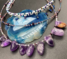 Load image into Gallery viewer, The Genuine Amethyst Natural Gemstone Adjustable Chocker Style Glass Beaded Necklace features vibrant violet and white tones. Its unique draped beading creates a beautiful style with a series of short strands of glass beads for movement and a longer strand with a multitude of amethyst nugget beads. The collar necklace hangs gracefully along the neck and chest, making it a dream come true for violet lovers.  Measurements:  Necklace is 15” in length adjustable to 18" in length