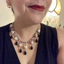 Load image into Gallery viewer, Black And White Vampire Goth Skulls Choker Style Necklace, Skully Witchy Vibe, Goth Dark Souls Jewelry, Day Of The Dead, Dia De Los Muertos, Howlite Skull Beads Black And Silver Glass BeadsThis statement necklace radiates a dark, shimmering aesthetic with two strands of glass beads connected through double-hole silver and black beads to create a collar shape. These dangling skulls beads are acompanied by black teardrop glass beads enable the piece to flow elegantly and express a bold, fierce look.