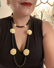 Load image into Gallery viewer, This Cocktail Chic Long Beaded Necklace is a unique piece that can be styled in different ways. Crafted with black flat matte glass beads for a luxurious look, the necklace is complemented by small and large white rose beads for contrast. The intricate petal details give the piece an extra special touch. This set is a simple and elegant pieces, very versatile looks and comes with a pair of matching earrings. Perfect cocktail chic attire, fancy wedding necklace, a minimalist look.
