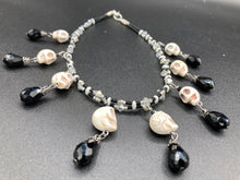 Load image into Gallery viewer, Black And White Vampire Goth Skulls Choker Style Necklace, Skully Witchy Vibe, Goth Dark Souls Jewelry, Day Of The Dead, Dia De Los Muertos, Howlite Skull Beads Black And Silver Glass BeadsThis statement necklace radiates a dark, shimmering aesthetic with two strands of glass beads connected through double-hole silver and black beads to create a collar shape. These dangling skulls beads are acompanied by black teardrop glass beads enable the piece to flow elegantly and express a bold, fierce look.