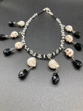 Load image into Gallery viewer, Black And White Vampire Goth Skulls Choker Style Necklace, Skully Witchy Vibe, Goth Dark Souls Jewelry, Day Of The Dead, Dia De Los Muertos, Howlite Skull Beads Black And Silver Glass BeadsThis statement necklace radiates a dark, shimmering aesthetic with two strands of glass beads connected through double-hole silver and black beads to create a collar shape. These dangling skulls beads are acompanied by black teardrop glass beads enable the piece to flow elegantly and express a bold, fierce look.