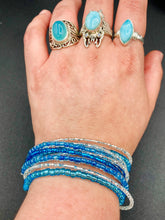 Load image into Gallery viewer, This bracelet is a chic, minimalistic design with nine beaded strands that feature various blue and silver glass beads. It measures 7 1/2" in length and has been crafted with inspiration from the ocean blue waves.