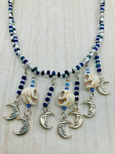 Load image into Gallery viewer, Howlite Skull Beads And Smiling Crescent Moon Charms Choker Style Glass Beaded Necklace. Two beaded stands that are primarily white and added purple glass beads that have hues of blue and gold. I wanted to incorporate dark and white glass bead colors to create a simple contrast. Large amount of dangling skulls and their smiling crescent moons add a lot of movement. Necklace is 16”adjustable up to 18" in length - hanging howlite skull with crescent moons are 2” Height