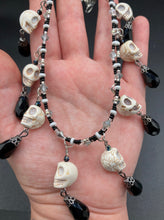 Load image into Gallery viewer, Black And White Vampire Goth Skulls Choker Style Necklace, Skully Witchy Vibe, Goth Dark Souls Jewelry, Day Of The Dead, Dia De Los Muertos, Howlite Skull Beads Black And Silver Glass BeadsThis statement necklace radiates a dark, shimmering aesthetic with two strands of glass beads connected through double-hole silver and black beads to create a collar shape. These dangling skulls beads are acompanied by black teardrop glass beads enable the piece to flow elegantly and express a bold, fierce look.