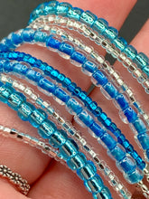 Load image into Gallery viewer, This bracelet is a chic, minimalistic design with nine beaded strands that feature various blue and silver glass beads. It measures 7 1/2" in length and has been crafted with inspiration from the ocean blue waves.
