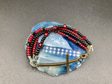 Load image into Gallery viewer, For Positivity and Faith, Shimmery Red And Black Glass Beaded Bracelet With Curved Horizontal Brass Cross. This bracelet has a large brass cross that is slightly curved to be comfortably worm around your wrist.  I created four different black and red glass beads strands. Measurements: 7 1/2" in length, brass cross measures 2" in length.