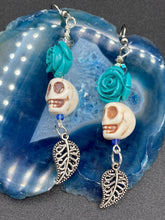 Load image into Gallery viewer, Frida Kahlo Inspired Earrings, Howlite Skull And Turquoise Quartize Floral Beads. This beautifully and elegant set of earrings captures Frida Kahlo's signature floral crown on her head. Dangling silver plated intricate leaf at the bottom to give these earrings some movement. These are a beautiful piece of jewelry to wear for inspiration or a great Dia De Los Muertos jewelry piece. Chingona, Cabrona, Latina Chicana, Goth, Vampire Goth, Dark Witchy Style. 2 ” in length