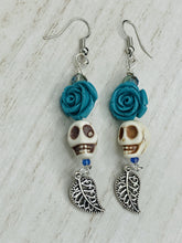 Load image into Gallery viewer, Frida Kahlo Inspired Earrings, Howlite Skull And Turquoise Quartize Floral Beads. This beautifully and elegant set of earrings captures Frida Kahlo's signature floral crown on her head. Dangling silver plated intricate leaf at the bottom to give these earrings some movement. These are a beautiful piece of jewelry to wear for inspiration or a great Dia De Los Muertos jewelry piece. Chingona, Cabrona, Latina Chicana, Goth, Vampire Goth, Dark Witchy Style. 2 ” in length
