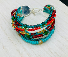 Load image into Gallery viewer, Vibrant And Enchanting Southwest Style Jewelry. This stunningly bold statement piece contains nine beaded strands full of variant turquoise, bright and dark reds and greens, golds and yellows. I created this beautiful jewelry piece by using a wide variety of different bead shapes from large and small round, round tubes, and squares. Measurements: 7 1/2" in length