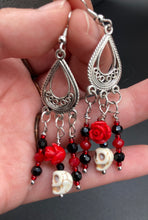 Load image into Gallery viewer, Frida Kahlo Inspired Earrings, Tiny Howlite Skull Beads With Red Quartize Rose Beads. Elegant set of earrings captures Frida Kahlo's signature floral crown on her head. Red and black shimmery glass beads to give a little pop of color and incorporated some movement. These are a beautiful piece of jewelry to wear for inspiration or a great Dia De Los Muertos jewelry piece. You can dress these up or down, it will definitely give your outfit a unique look. 2 ” in length