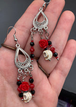 Load image into Gallery viewer, Frida Kahlo Inspired Earrings, Tiny Howlite Skull Beads With Red Quartize Rose Beads. Elegant set of earrings captures Frida Kahlo's signature floral crown on her head. Red and black shimmery glass beads to give a little pop of color and incorporated some movement. These are a beautiful piece of jewelry to wear for inspiration or a great Dia De Los Muertos jewelry piece. You can dress these up or down, it will definitely give your outfit a unique look. 2 ” in length