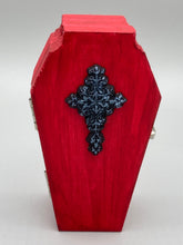 Load image into Gallery viewer, This unique ring box is sure to make an impression, with its simple but vibrant red coffin design and eye-catching black and gray floral cross in the center. The interior is black with a detailed fleur de lis, making the perfect resting place for your voodoo doll. It's spooky but also cute, with its accompanying Misfit VooDoo Doll.