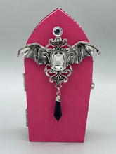 Load image into Gallery viewer, This unique handmade Pink Spooky Glam Wood Coffin Ring Box offers a statement piece for your witchy home decor. Its macabre collections boast a black and pink wood coffin with large shimmery bat embellishments and decorative black crystals around the exterior. Open up the box to find a bright turquoise mandala fabric and a tiny black crystal bat decoration for a truly eerie feel.