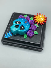 Load image into Gallery viewer, Showcasing a dark theme Frida Kahlo inspired calavera with a dark wood frame, this Day of the Dead wall decor piece is perfect for adding a traditional Mexican folk art touch to any home. Featuring an intricately detailed clay calavera in the style of Frida Kahlo, this Day of the Dead wall art decor is sure to be the centerpiece of any home décor. The calavera is wearing Frida's iconic crown of flowers, ensuring it will bring both a unique and inspiring look to any wall.