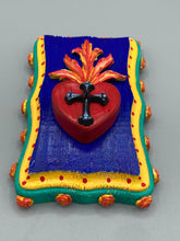 Load image into Gallery viewer, This Sacred Heart Wall Art Decor is the perfect way to enhance your home with an artistic flair. This Sacred Heart Wall Art Decor is crafted with a stunning red heart detailed with a black-silver cross and a vibrant fire embellishment at its center. Adding to its unique traditional Mexican aesthetic, the wood frame is decorated with marigold flowers, creating a beautiful and eye-catching artwork.
