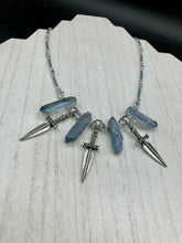 Load image into Gallery viewer, This elegant and dark necklace features shimmering light silver and gray glass beads of varying sizes and shapes for texture and dimension. The necklace is finished with blue luster crystal stone nuggets and nickel-free dagger pendants, creating a beautiful draping effect. Measurements:   Necklace is 17”adjustable up to 19"