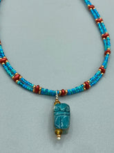 Load image into Gallery viewer, This adjustable choker style necklace features an eye-catching teal wood scarab beetle pendant and glass beaded strands. This dramatic necklace is kept together by double-hole flat matte lava-red beads, providing a collar shape. The necklace artfully wraps around the neck, conveying an elegant and bold style.  Measurements:    Necklace is 14 1/2” in length, can be adjusted up to 16"