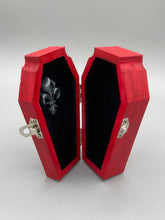 Load image into Gallery viewer, This unique ring box is sure to make an impression, with its simple but vibrant red coffin design and eye-catching black and gray floral cross in the center. The interior is black with a detailed fleur de lis, making the perfect resting place for your voodoo doll. It's spooky but also cute, with its accompanying Misfit VooDoo Doll.