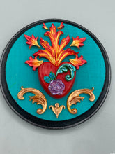 Load image into Gallery viewer, This Sacred Heart Wall Art Decor is the perfect way to enhance your home with an artistic flair. This beautiful artwork features a round bright turquoise wooden frame with a hand-crafted bright red heart. The heart is detailed with light purple and vibrant green leaves, with a vibrant fire embellishment over the center. Gold decorative embellishments at the sides of the heart add a luxurious touch. Diameter 4"