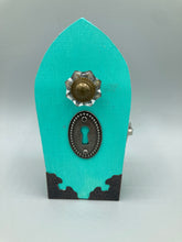 Load image into Gallery viewer, This Whimsical Fairy Wood Coffin Box is a truly unique and magical piece of home decor. With its vibrant turquoise exterior and eye-catching mini door knob, this Steampunk-inspired box is sure to be a conversation starter. Inside, the glittery gold interior and colorful butterfly detailing will bring a touch of fantasy to any room. The silver key and accompanying iridescent crystals complete the mystical and pastel goth look!