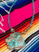 Load image into Gallery viewer, This vibrant and striking double strand necklace features a combination of glass beads in blue and green shades of turquoise, gold and champagne. The two delicate strands are accented with a gold-tone flower-shaped bead, a howlite stone chip dyed in turquoise, and shimmery, cross-faceted champagne-colored glass beads to complete the dramatic look. Measurements: Necklace is 17” and can be adjusted up to 19"