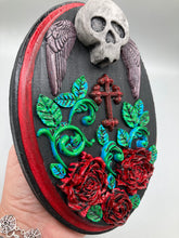 Load image into Gallery viewer, This Memento Mori Wall Art Decor is a one-of-a-kind art piece, skillfully crafted with a black polymer clay skull and wings on a dark red wood frame, decoratively woven with dark red roses and vines. It's perfect for adding an eye-catching touch to any wall and makes a unique, bold gift.  Measurements: H 7" x W 5” x D 1 1/2"