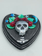 Load image into Gallery viewer, Showcasing a dark theme Frida Kahlo inspired calavera with a dark wood frame, this Day of the Dead wall decor piece is perfect for adding a traditional Mexican folk art touch to any home. Featuring an intricately detailed clay calavera in the style of Frida Kahlo, this Day of the Dead wall art decor is sure to be the centerpiece of any home décor. The calavera is wearing Frida's iconic crown of flowers, ensuring it will bring both a unique and inspiring look to any wall.