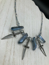 Load image into Gallery viewer, This elegant and dark necklace features shimmering light silver and gray glass beads of varying sizes and shapes for texture and dimension. The necklace is finished with blue luster crystal stone nuggets and nickel-free dagger pendants, creating a beautiful draping effect. Measurements:   Necklace is 17”adjustable up to 19"