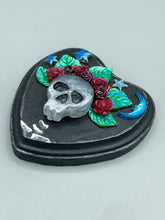 Load image into Gallery viewer, Showcasing a dark theme Frida Kahlo inspired calavera with a dark wood frame, this Day of the Dead wall decor piece is perfect for adding a traditional Mexican folk art touch to any home. Featuring an intricately detailed clay calavera in the style of Frida Kahlo, this Day of the Dead wall art decor is sure to be the centerpiece of any home décor. The calavera is wearing Frida's iconic crown of flowers, ensuring it will bring both a unique and inspiring look to any wall.
