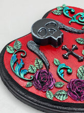 Load image into Gallery viewer, This Memento Mori Wall Art Decor is a one-of-a-kind art piece, skillfully crafted with a black polymer clay skull and wings on a dark red wood frame, decoratively woven with dark red roses and vines. It's perfect for adding an eye-catching touch to any wall and makes a unique, bold gift. Measurements: H 6 3/4" x W 7” x D 1 1/2"
