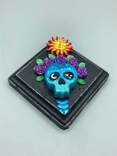 Load image into Gallery viewer, Showcasing a dark theme Frida Kahlo inspired calavera with a dark wood frame, this Day of the Dead wall decor piece is perfect for adding a traditional Mexican folk art touch to any home. Featuring an intricately detailed clay calavera in the style of Frida Kahlo, this Day of the Dead wall art decor is sure to be the centerpiece of any home décor. The calavera is wearing Frida's iconic crown of flowers, ensuring it will bring both a unique and inspiring look to any wall.