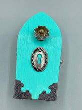Load image into Gallery viewer, This Whimsical Fairy Wood Coffin Box is a truly unique and magical piece of home decor. With its vibrant turquoise exterior and eye-catching mini door knob, this Steampunk-inspired box is sure to be a conversation starter. Inside, the glittery gold interior and colorful butterfly detailing will bring a touch of fantasy to any room. The silver key and accompanying iridescent crystals complete the mystical and pastel goth look!