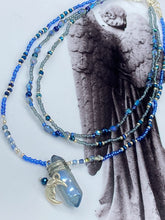 Load image into Gallery viewer, This jewelry piece is a delicate harmony of light and dark tones. Three strands feature a mix of navy blue, pewter, and oval-shaped, light blue-gray beads with a subtle iridescence of amethyst, emerald, and gold. Its celestial theme and bold composition create an alluringly elegant accessory. This whimsical necklace boasts a wonderfully unique aesthetic, featuring a wired blue luster nugget and a whimsical crescent moon charm. Measurements: Necklace is 15 1/4”adjustable up to 18"