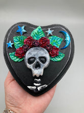 Load image into Gallery viewer, Showcasing a dark theme Frida Kahlo inspired calavera with a dark wood frame, this Day of the Dead wall decor piece is perfect for adding a traditional Mexican folk art touch to any home. Featuring an intricately detailed clay calavera in the style of Frida Kahlo, this Day of the Dead wall art decor is sure to be the centerpiece of any home décor. The calavera is wearing Frida's iconic crown of flowers, ensuring it will bring both a unique and inspiring look to any wall.