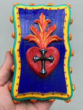 Load image into Gallery viewer, This Sacred Heart Wall Art Decor is the perfect way to enhance your home with an artistic flair. This Sacred Heart Wall Art Decor is crafted with a stunning red heart detailed with a black-silver cross and a vibrant fire embellishment at its center. Adding to its unique traditional Mexican aesthetic, the wood frame is decorated with marigold flowers, creating a beautiful and eye-catching artwork.