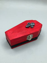 Load image into Gallery viewer, Super vibrant red coffin box has an eye-catching black and gray embellishment in the center, accompanied by a glittery black ribbon around the coffin. Inside, the interior is all black with a floral detailed black-silver cross.