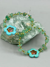 Load image into Gallery viewer, This pair of earrings features a turquoise magnesite floral bead with a vibrant orange glass bead and natural green aventurine stone chips juxtaposed against gold and blue glass beads.  Measurements: 2&quot; length 
