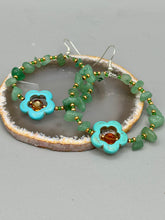 Load image into Gallery viewer, This pair of earrings features a turquoise magnesite floral bead with a vibrant orange glass bead and natural green aventurine stone chips juxtaposed against gold and blue glass beads.  Measurements: 2&quot; length 
