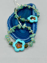 Load image into Gallery viewer, This pair of earrings features a turquoise magnesite floral bead with a vibrant orange glass bead and natural green aventurine stone chips juxtaposed against gold and blue glass beads. Measurements: 2&quot; length 
