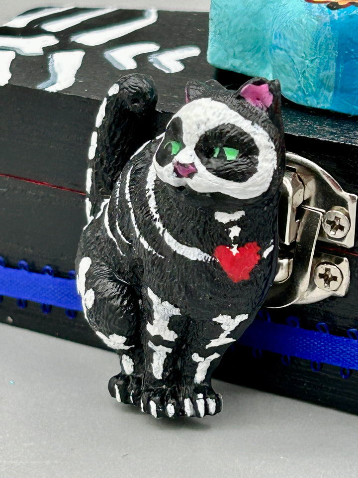 This hand-crafted art magnet featuring a skeleton cat is the ideal home decor for cat lovers, Halloween or Day Of The Dead enthusiasts. Perfect for adorning fridges, lockers, cubicles, and toolboxes.   I wanted to create an art piece that represented the eternal love for a special kitty cat in your life. Add a little touch of Mexican art to your home or office. This Day Of The Dead art was created for the cat lovers who adore their sweet kitty. H 2” x W 1/2” x D 3/8” 